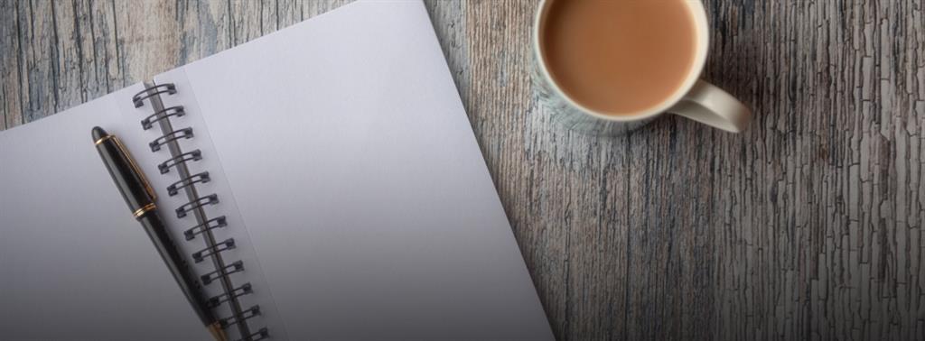 coffee cup and notpad on a desk